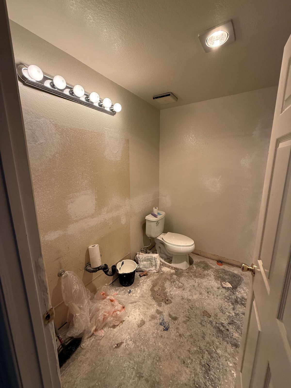 Bathroom before renovation, stripped down to bare walls and toilet