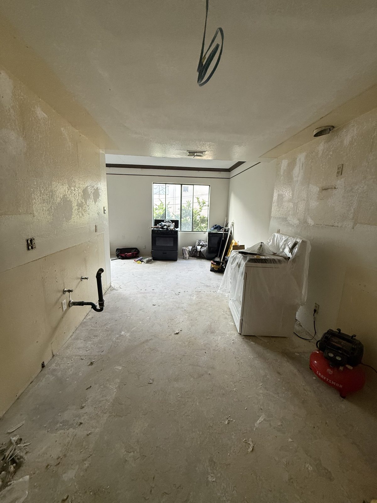 Kitchen before renovation, gutted with appliances in the middle of the room